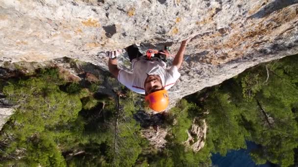 Man lood klimmen in de natuur rots aan zee, in Andratx kustlijn, Mallorca eiland, Spanje.Low angle, 4K 60p. - Video