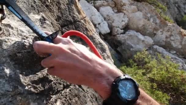 Man lead climbing in nature rock and cliping the final quickdraw, next to sea, in Andratx coastline, Mallorca island, Spain.Close up, low angle, twist movement, 4K 60p. - Footage, Video