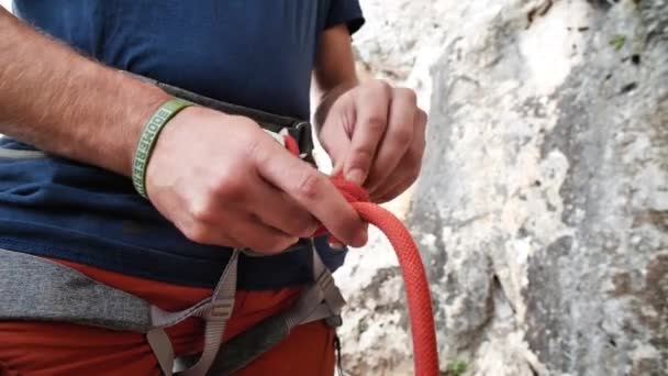 Muž svazuje bezpečnostní uzel, připravuje se na lezení, v Betlemu, Mallorce, Španělsku.Střední úhel, paralaxní pohyb, 4K 60p. - Záběry, video