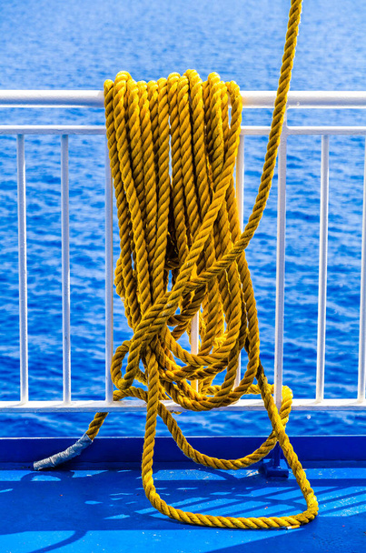 Κοντινό πλάνο του κίτρινου πλεγμένου σχοινιού πάνω από ένα κιγκλίδωμα πλοίου - Φωτογραφία, εικόνα