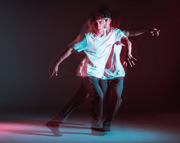 Cool guy breakdancer dancing hip-hop in neon light. Dance school poster. Long exposure shot - 写真・画像