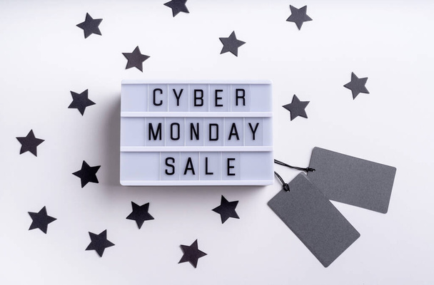 Cyber Mnday shopping concept. Cyber Monday Sale words on lightbox with black price tags and confetti top view flat lay on white background - Foto, Imagem