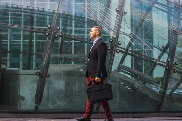 Foto de un joven y atractivo hombre de negocios vestido con ropa elegante con un maletín listo para comenzar su día de trabajo - Foto, Imagen