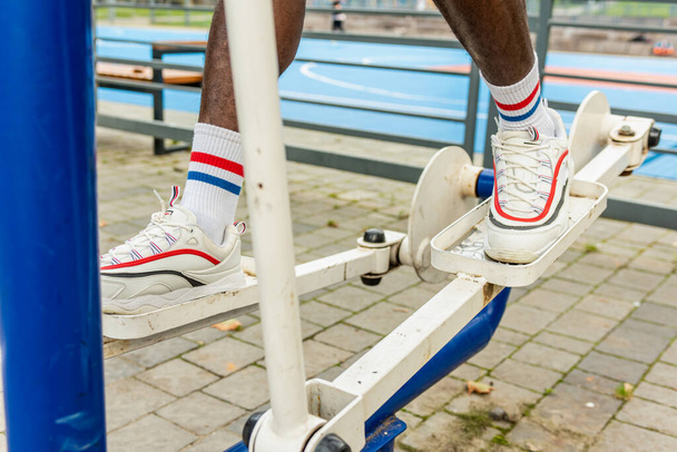 屋外フィットネス(スポーツグラウンド上の運動マシン上の男性の足) - 写真・画像