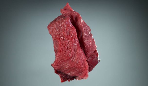 Raw beef steaks flying up in the air, isolated on grey background - Foto, Bild