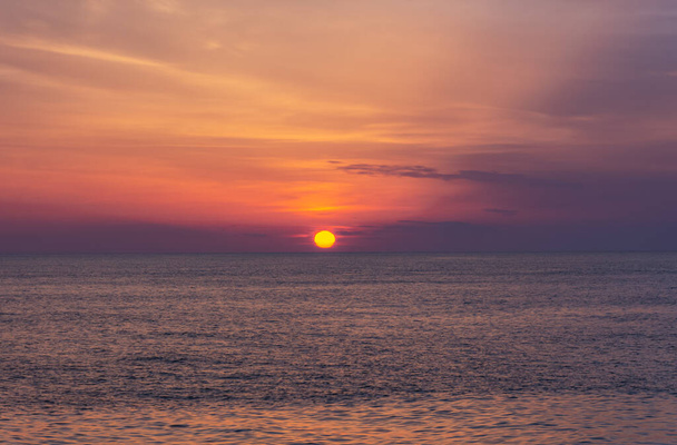 海の上に美しいオレンジ色の夕日。太陽は地平線に沈む。リラックスした海の風景。空と海の水の紫色の色合い。黒海に沈む夕日。自然の背景. - 写真・画像