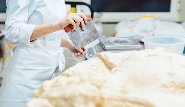 Baker measuring dough to make a bread - Foto, Bild