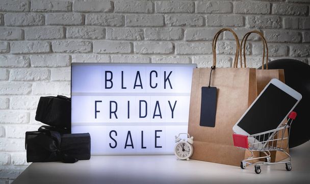 Black Friday Shopping Sale Konzept. Black friday Sale words on lightbox with black price tag and gifts front view on dark background - Foto, Bild
