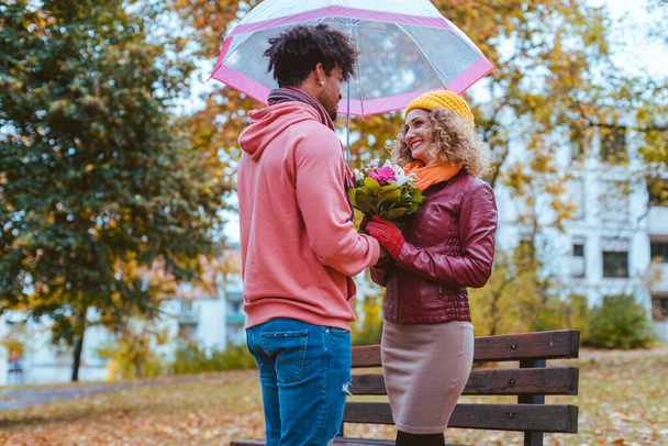 Musta mies antaa kukkia hänen valkoihoinen tyttöystävä syksyllä - Valokuva, kuva