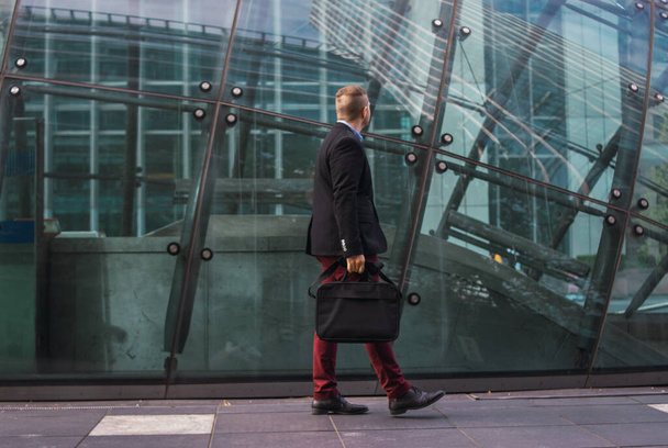 Фото молодого и привлекательного бизнесмена в умной одежде с портфелем, готовым начать рабочий день - Фото, изображение