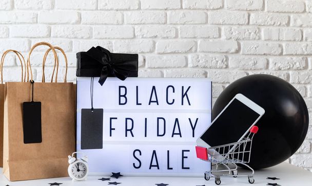 ブラックフライデーのショッピングセールのコンセプト。ブラック・フライデー闇の背景に黒い値札とプレゼントのフロントビューを持つライトボックス上の販売の言葉 - 写真・画像