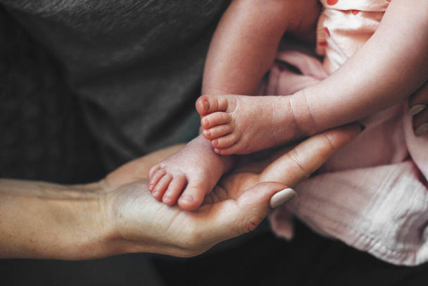 close up photo of a caucasian mother touching her newborn babys feet with palm - Photo, Image