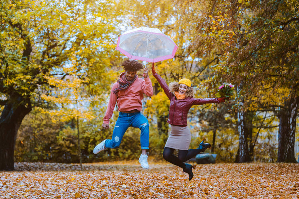 Мужчина и женщина с радостью прыгают в осеннем парке - Фото, изображение