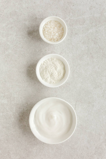 Three various natural spa cosmetics products in a bowl: facial cream, cosmetic clay, sea salt on gray marble background. Skincare concept.  - Photo, image