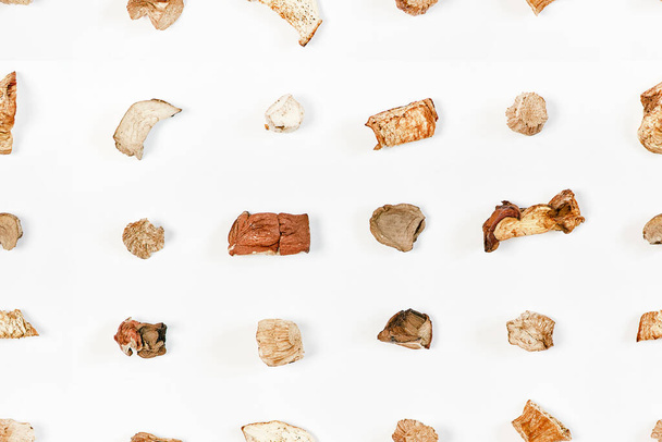 Seamless pattern from pieces of dried mushrooms scattered by lines on a light background. View from above - Fotó, kép