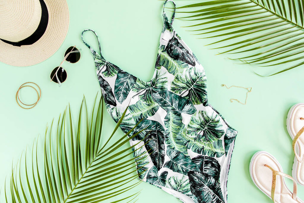 Womans beach accessories: bikini, rattan bag, straw hat, tropical palm leaves on yellow background. Summer background.  - Fotó, kép