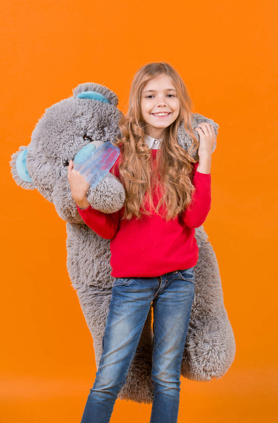 Girl hug big teddy bear on orange background - 写真・画像