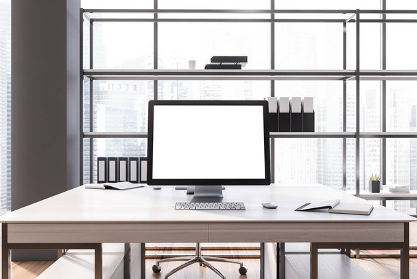Computer with mock up screen standing on white table in stylish open space office with gray walls and wooden floor. 3d rendering - Foto, Bild