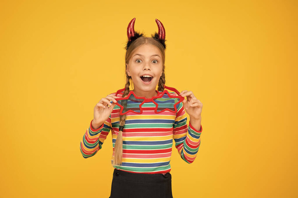 Cute but dangerous. Halloween concept. Preparing for party. Start this party. Party attributes. Playful demon girl. Small child with red horns and eyewear. Accessories for carnival. Girlish temper - Foto, Bild