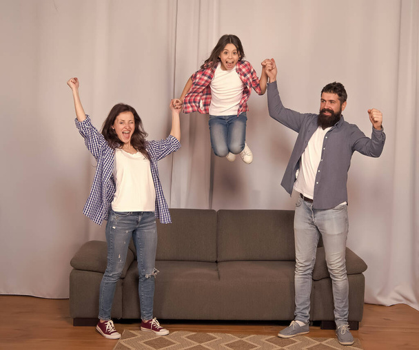 Higher. Friendly family jump couch Mom dad and daughter relaxing. We are family. Happy family spend weekend together. Our home made for fun. Togetherness and bonds. Good vibes. Positive emotions - 写真・画像