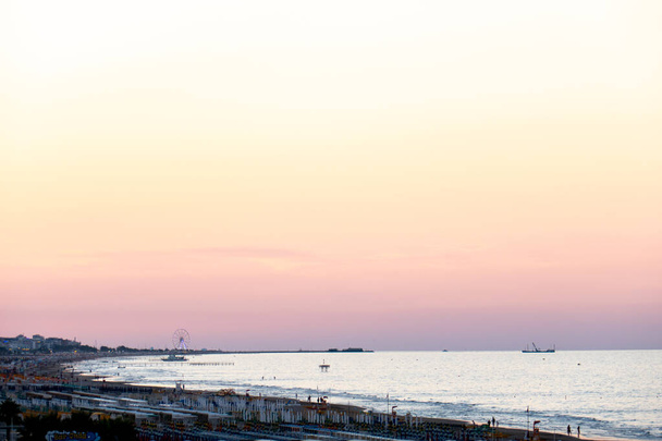 Minimální krajina pobřeží Jaderského moře v Rimini a Riccione při západu slunce, s barevnou oblohou a panoramatickým kolem na pozadí - Fotografie, Obrázek