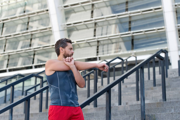 Sportsman warming up before workout in front of stadium, healthy lifestyle concept - Photo, Image