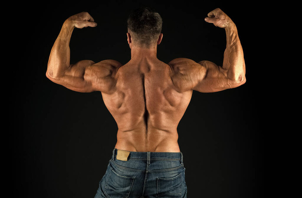 Exercises for back. Bodybuilder perfect shape rear view. Strong bodybuilder flexing arms muscles black background. Fit bodybuilder showing muscular body. Professional coach demonstrate achievements - Photo, Image