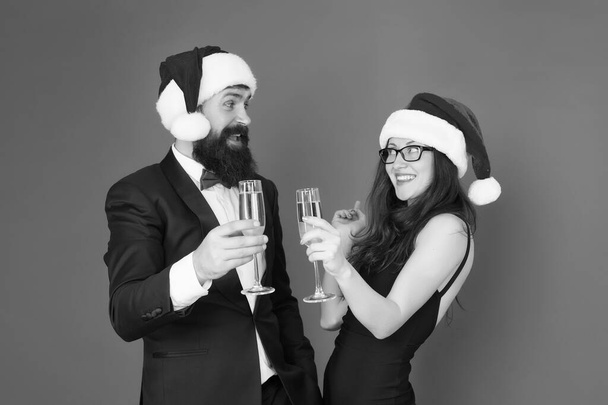 Lets have fun. Office party. Winter party. Merry christmas. Couple at corporate party. Happy new year. Bearded businessman in tuxedo and girl elegant dress drinking sparkling wine red background - Valokuva, kuva
