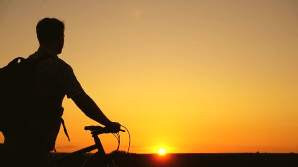 viajero libre viaja en bicicleta al atardecer. joven saludable en bicicleta a lo largo del borde de la colina disfrutando de la naturaleza y el sol. Un ciclista solitario descansando en el parque. concepto de aventura y viaje. - Imágenes, Vídeo