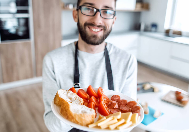 plate of sandwiches in the hands of an attractive man - Фото, изображение
