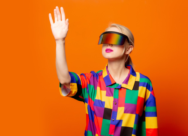 Style blonde in 90s clothes VR glasses on orange background - Foto, afbeelding