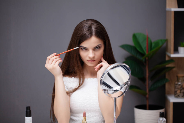 Young woman applying makeup on face at home - Photo, Image