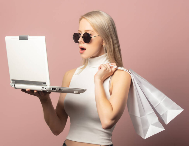 Style blonde in top with shopping bags and notebook on pink background  - Fotó, kép