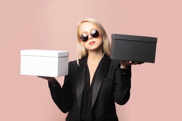 Style blonde in blazer and sunglasses with gift boxes on pink background - Photo, Image