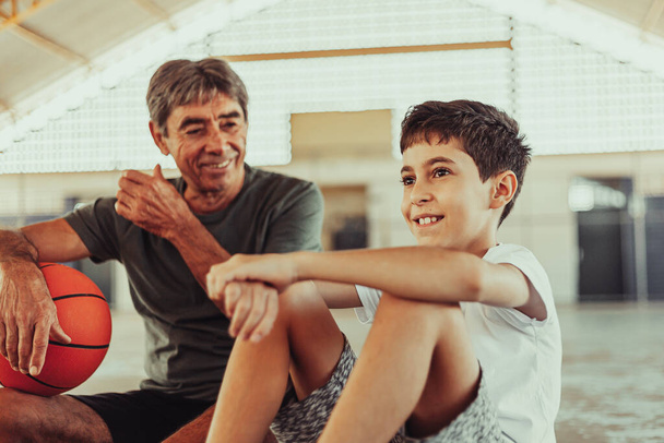 Latin grandfather and grandson playing basketball on the court - Fotoğraf, Görsel