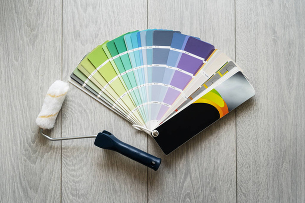 Top kilátás színes paletta és festék görgő a fapadlón otthon - Felújítás és ház javítás koncepció - Fotó, kép