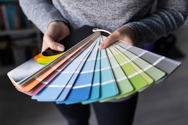 Gros plan sur les mains d'une femme inconnue tenant une palette de couleurs à la maison dans l'appartement - Femme choisissant un matériau de peinture pour la rénovation de la maison - concept de décoration et d'innovation - Photo, image