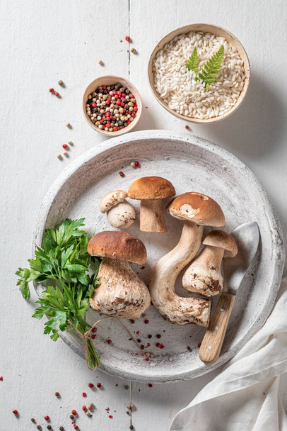 Ingredients for vegetarian risotto with boletus mushrooms and parsley on wooden table - Photo, image