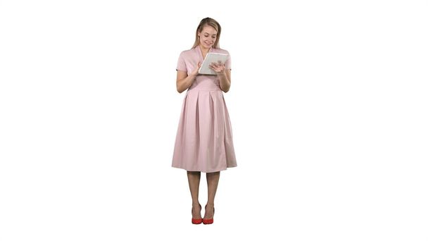 Pretty young woman in pink dress holding tablet and looking on i - Photo, Image