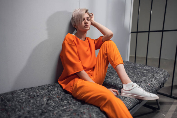 Menina condenada traficante de drogas em um macacão laranja em sua cela em um beliche da prisão - Foto, Imagem