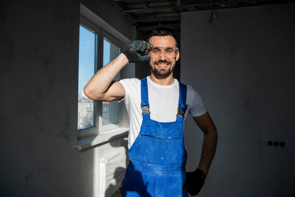 arbeider in blauwe overall en bril glimlachend - Foto, afbeelding