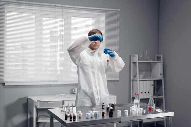 Banco di lavoro di un laboratorio di ricerca in cui uno scienziato mette una goccia di pipettatura di reagente in una provetta - Foto, immagini