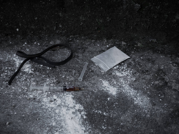 Héroïne en seringue et héroïne en poudre dans un sac en plastique avec élastique sur le sol en ciment sale. Substance addictive ou concept narcotique. - Photo, image