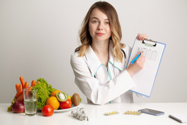 Молодой врач-диетолог пишет план диеты, здоровое питание - Фото, изображение
