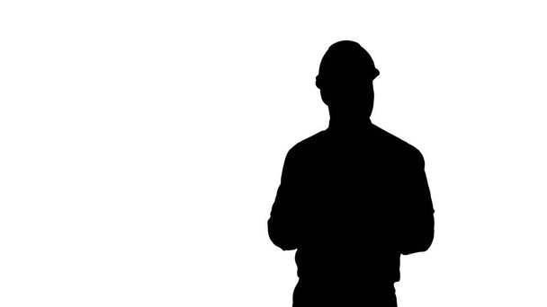 Silhouette Man in helmet and formal clothes walking looking around and making notes. - Фото, изображение