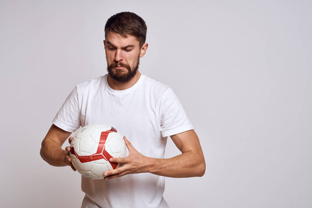 Muž trenér s fotbalovým míčem v ruce na lehkém pozadí energie vysvětlení pohybů - Fotografie, Obrázek