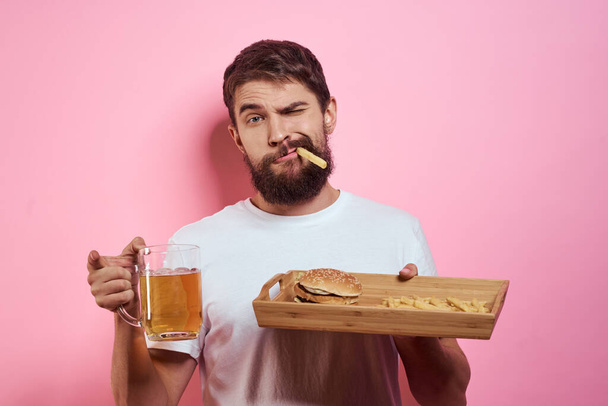 Man with tray of fast food and mug of beer french fries fast food cropped view - Foto, Imagem