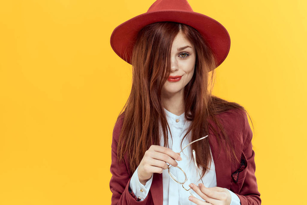 woman in red hat jacket glasses yellow background cosmetics - Foto, imagen