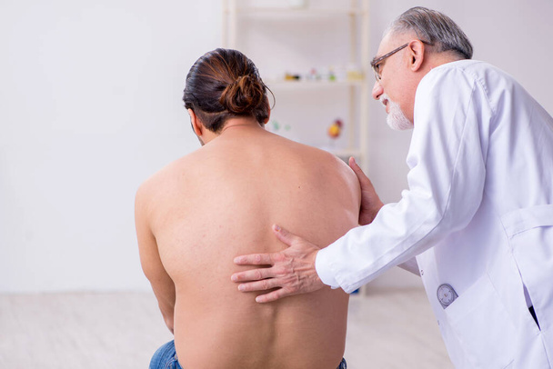 Jovem costas ferido homem visitando experiente médico masculino
 - Foto, Imagem