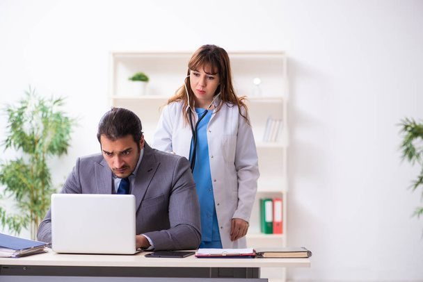 Jeune femme médecin et homme d'affaires malade dans le bureau - Photo, image